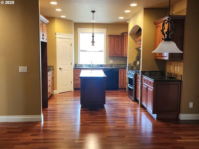 a kitchen with kitchen island granite countertop wooden floors and a sink