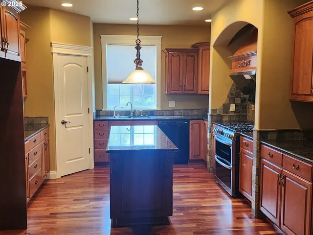 a kitchen with stainless steel appliances granite countertop a refrigerator a stove and a wooden floors