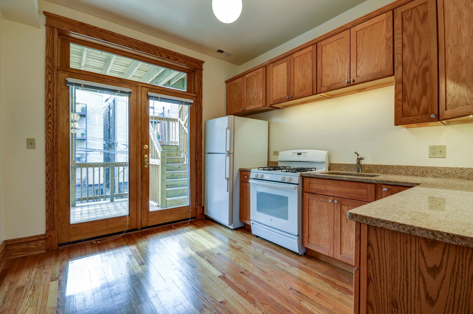 3722 North Fremont Street, Unit 2 Chicago, IL 60613 - Photo 5 of 16 a kitchen with stainless steel appliances granite countertop a refrigerator a sink dishwasher and wooden cabinets with wooden floor