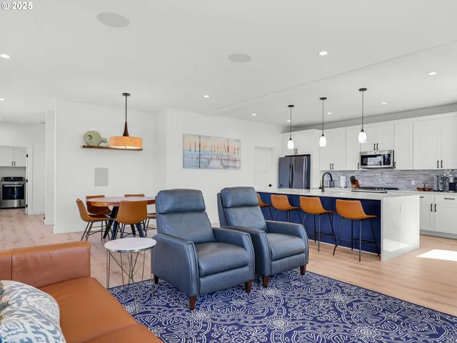 a living room with furniture kitchen view and a wooden floor
