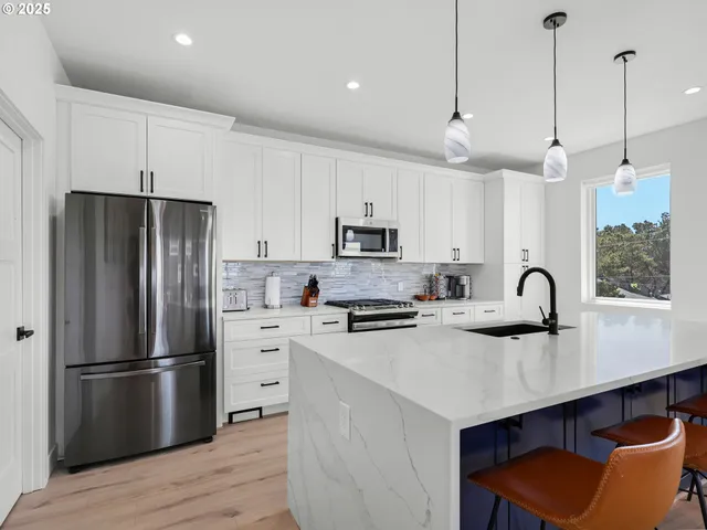 a kitchen with stainless steel appliances a refrigerator a sink a stove a center island and cabinets