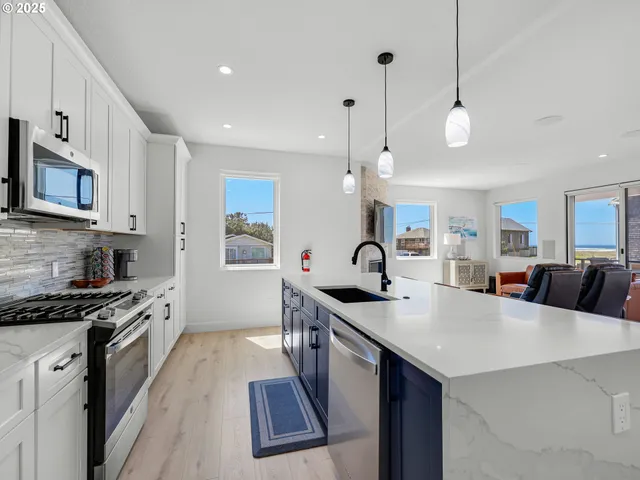 a kitchen with stainless steel appliances a stove a sink a microwave a center island and cabinets