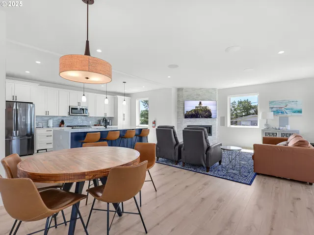 a kitchen with stainless steel appliances granite countertop a dining table chairs refrigerator and sink