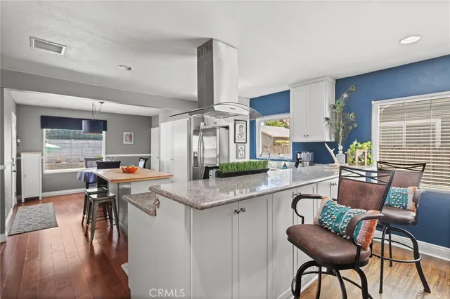 a kitchen with stainless steel appliances granite countertop a table chairs and a living room