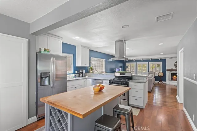 a kitchen with a refrigerator a stove top oven a sink dishwasher and white cabinets with wooden floor