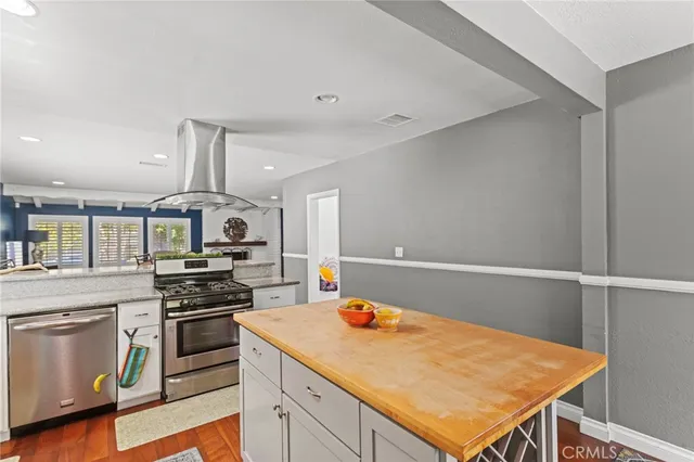 a kitchen with stainless steel appliances a stove cabinets and wooden floor
