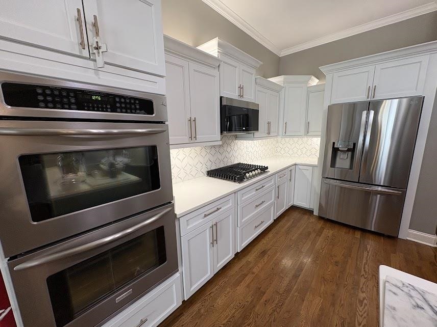 1307 Bull Creek Lane Collierville, TN 38017 - Photo 12 of 30 Kitchen featuring stainless steel appliances, backsplash, crown molding, white cabinets, and dark wood-type flooring