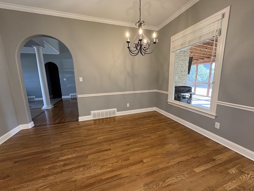 1307 Bull Creek Lane Collierville, TN 38017 - Photo 2 of 30 Unfurnished dining area featuring arched walkways, crown molding, dark wood-style floors, and a chandelier