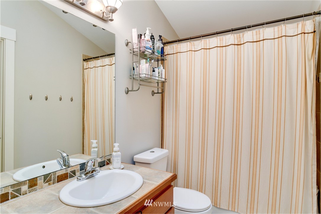 10303 Holman Road North, Unit C Seattle, WA 98177 - Photo 15 of 23 a bathroom with a sink a toilet and shower curtain