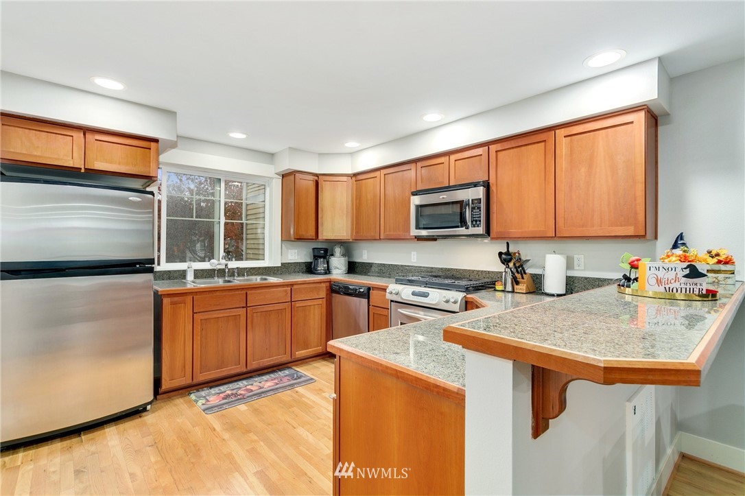 10303 Holman Road North, Unit C Seattle, WA 98177 - Photo 7 of 23 a kitchen with stainless steel appliances granite countertop sink stove top oven and cabinets