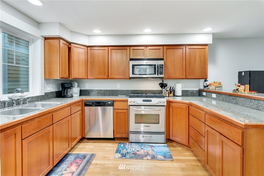 10303 Holman Road North, Unit C Seattle, WA 98177 - Photo 8 of 23 a kitchen with stainless steel appliances granite countertop a stove a sink and a microwave