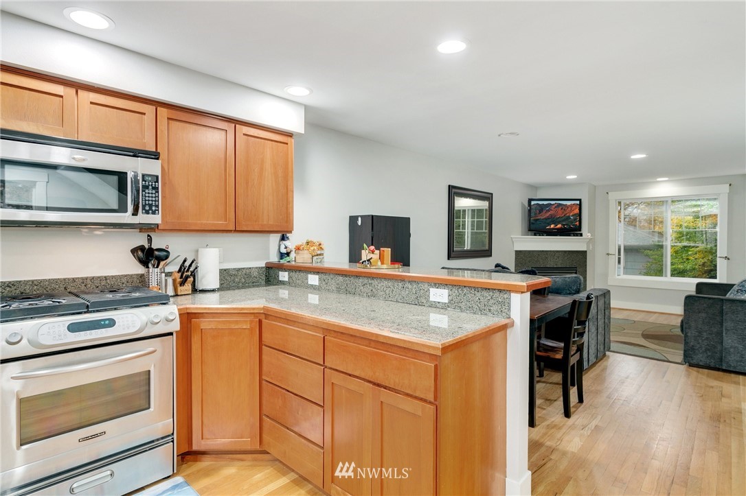 10303 Holman Road North, Unit C Seattle, WA 98177 - Photo 10 of 23 a kitchen with stainless steel appliances granite countertop a stove top oven a sink dishwasher and white cabinets with wooden floor