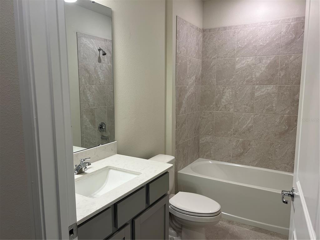 2007 Alluring Lane Davenport, FL 33896 - Photo 18 of 31 a bathroom with a granite countertop toilet a sink and a bathtub