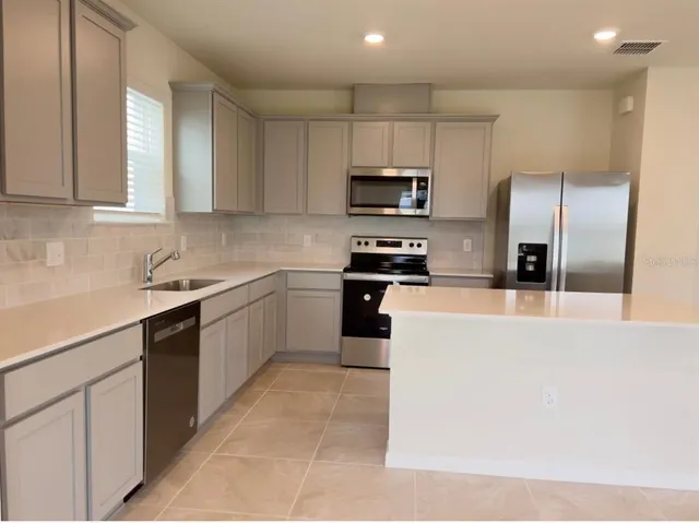 a kitchen with stainless steel appliances a refrigerator sink and microwave