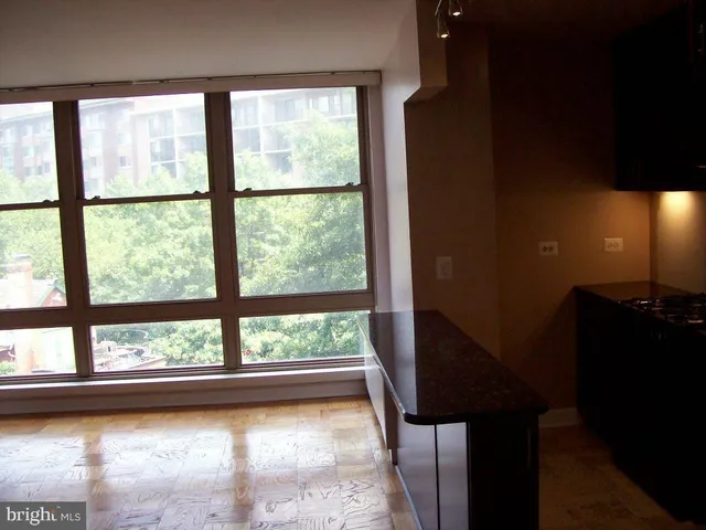 a view of a room with a large window and wooden floor