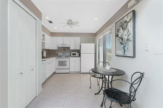 a kitchen with stainless steel appliances kitchen island a table chairs and a refrigerator