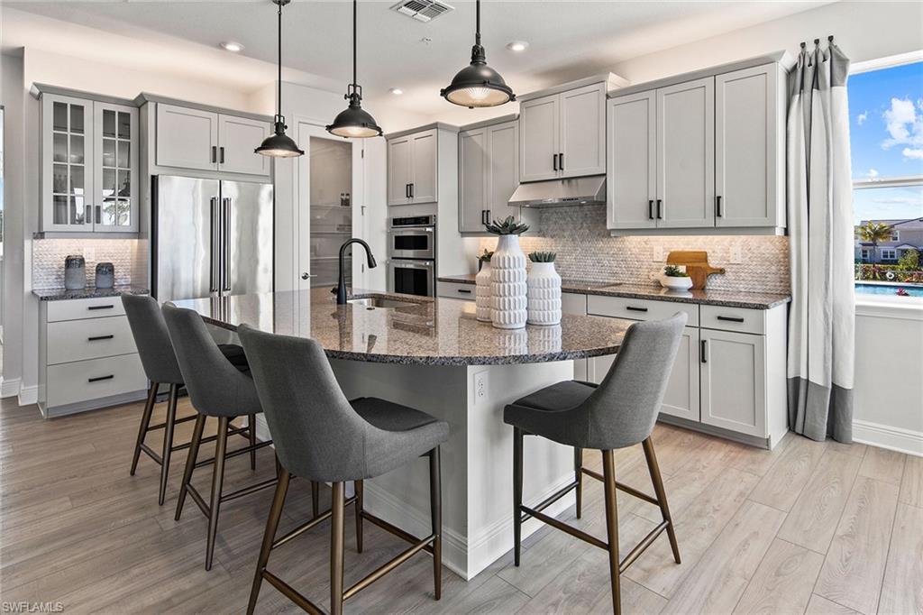 4551 Arboretum Circle, Unit 203 Naples, FL 34112 - Photo 5 of 22 a kitchen with stainless steel appliances granite countertop a dining table chairs and white cabinets