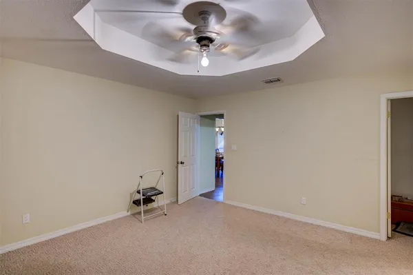an empty room with a chandelier fan and windows