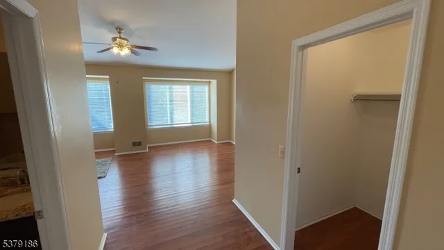 a view of an empty room with a window and wooden floor