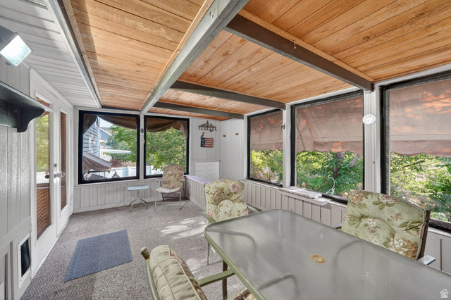 1464 990 West Provo, UT 84601 - Photo 35 of 41 Enclosed porch featuring a wood-panel ceiling with exposed beams, multiple windows, carpet flooring, and white paneled walls