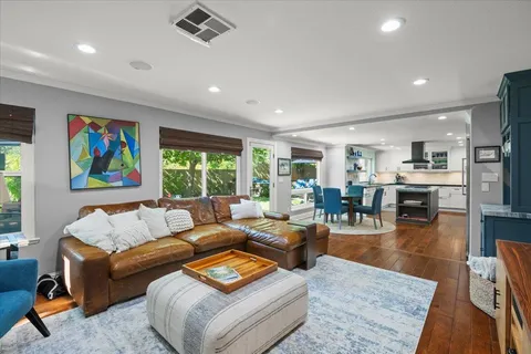 a living room with furniture kitchen view and a large window
