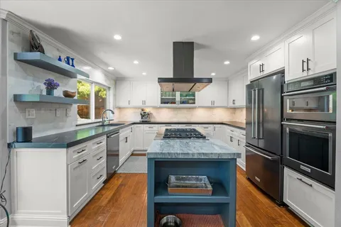 a kitchen with stainless steel appliances granite countertop a sink a stove and a refrigerator