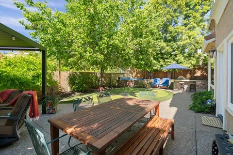a view of a patio with table and chairs potted plants and large tree