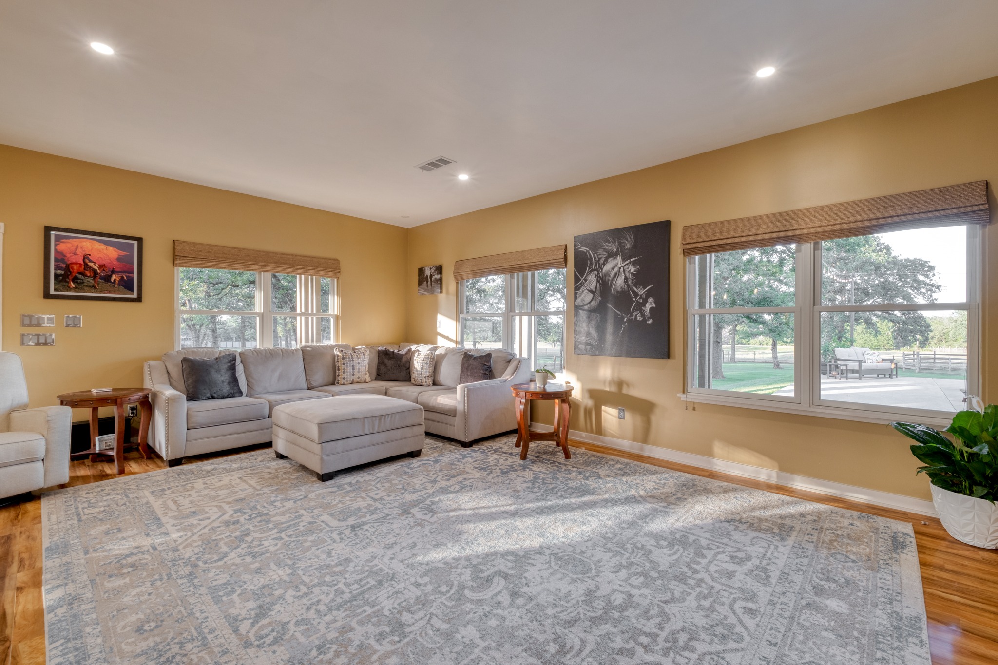 1474 County Rd B Lexington, TX 78947 - Photo 5 of 34 Sun-filled living area featuring rich hardwood flooring, recessed lighting, and large windows offering verdant outdoor views.