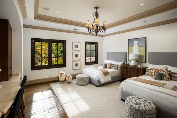 a spacious bedroom with a bed couch chandelier and a window