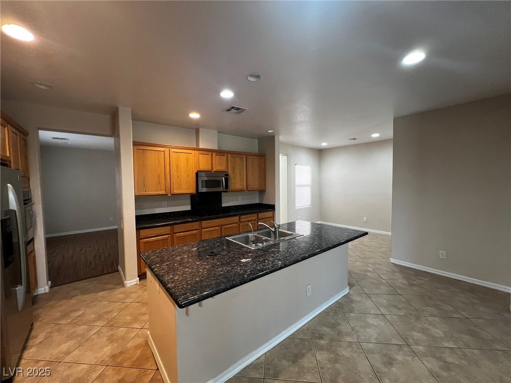 3417 West Birdwatcher Avenue North Las Vegas, NV 89084 - Photo 10 of 28 Kitchen featuring recessed lighting, stainless steel appliances, brown cabinets, light tile patterned flooring, and a center island with sink