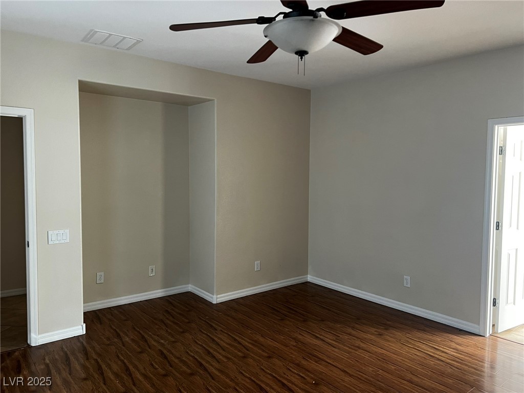 3417 West Birdwatcher Avenue North Las Vegas, NV 89084 - Photo 18 of 28 Unfurnished bedroom with dark wood-style flooring, ceiling fan, and connected bathroom