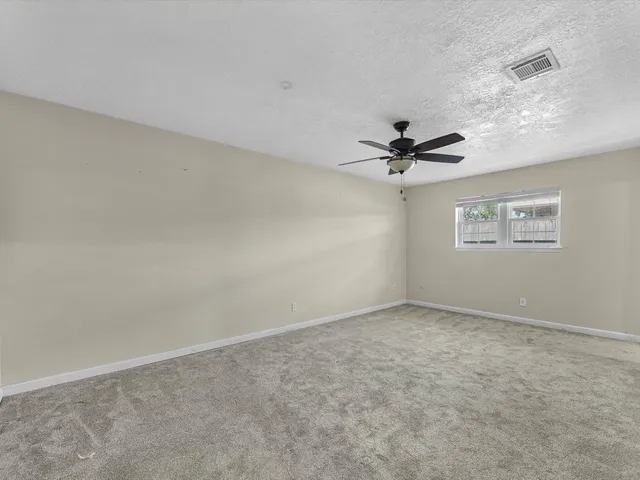 an empty room with a window and a ceiling fan