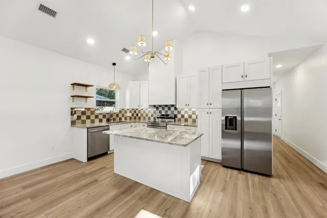 a kitchen with kitchen island a sink stainless steel appliances and cabinets