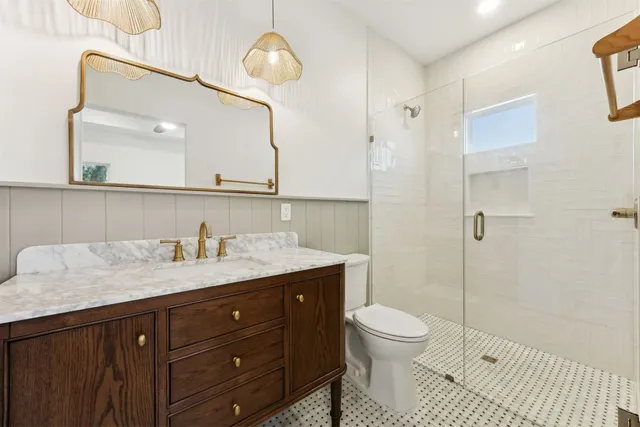 a bathroom with a granite countertop sink a toilet and a mirror