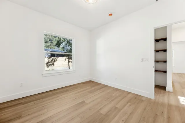 an empty room with wooden floor and windows