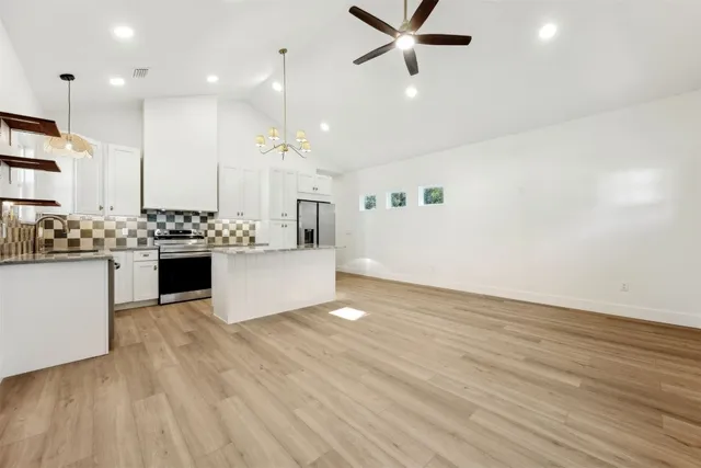 a kitchen with kitchen island a stove a sink and a refrigerator with wooden floor