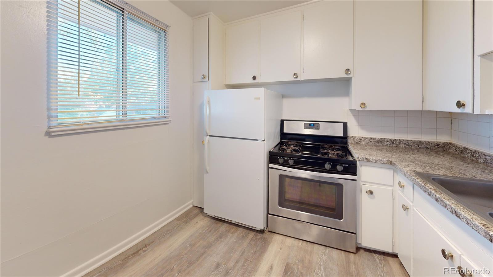1251 Upham Street, Unit 8 Lakewood, CO 80214 - Photo 4 of 38 a kitchen with granite countertop white cabinets and white appliances