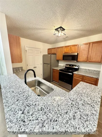 a kitchen with stainless steel appliances granite countertop a stove a sink and a microwave