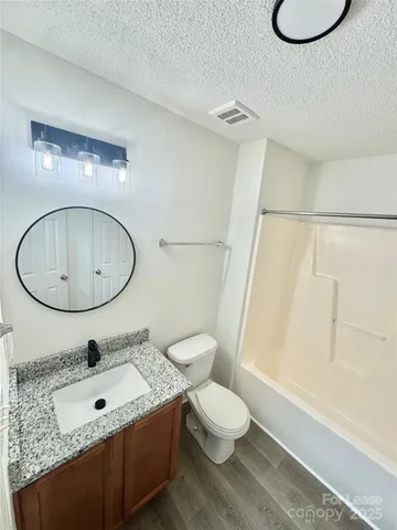 a bathroom with a granite countertop toilet sink and mirror