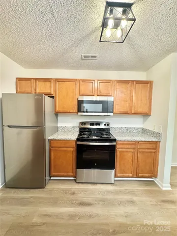 a kitchen with stainless steel appliances granite countertop a refrigerator a stove a sink and a microwave