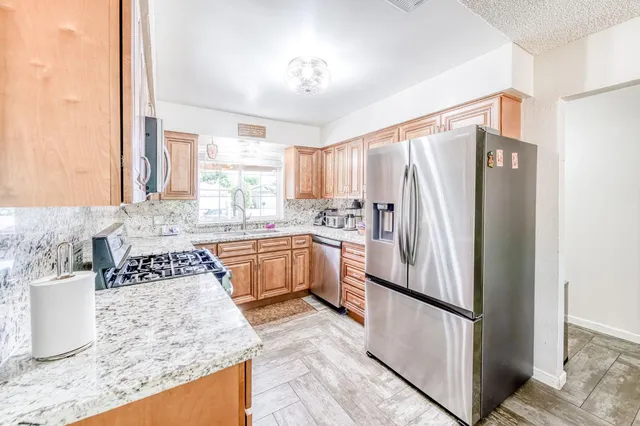 a kitchen with stainless steel appliances granite countertop a refrigerator sink and stove