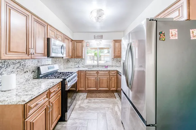 a kitchen with stainless steel appliances granite countertop a stove a sink and a refrigerator