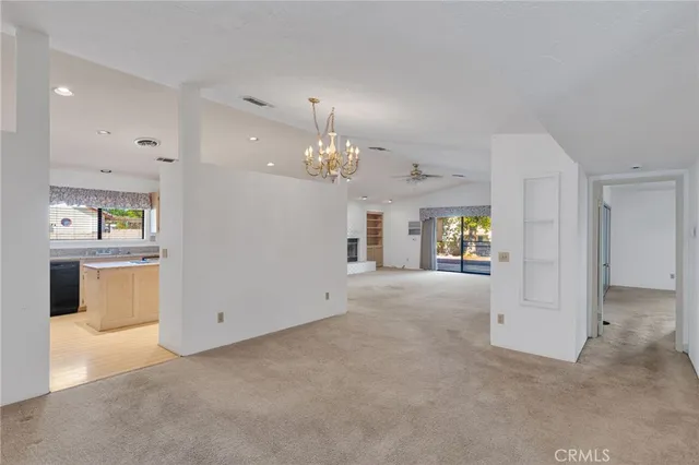 a view of an empty room with chandelier and wooden floor