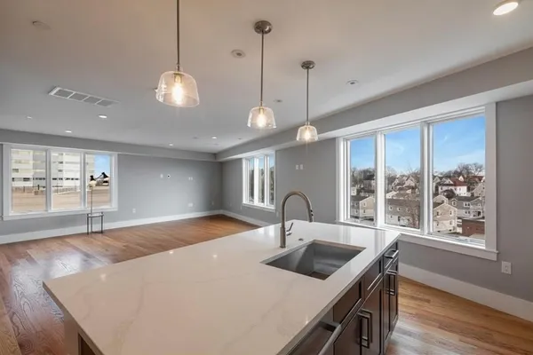 a kitchen with stainless steel appliances a sink a large window and wooden floors