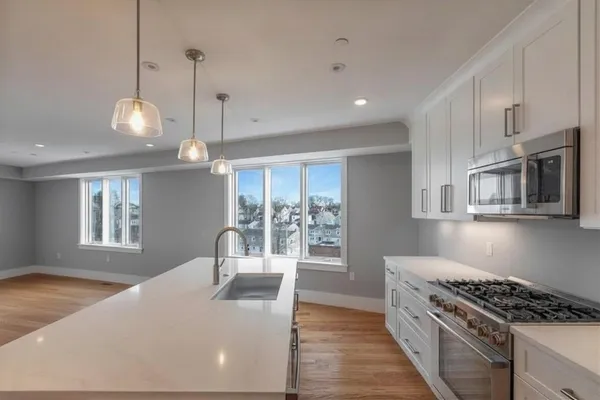 a kitchen with stainless steel appliances granite countertop a stove a sink and a refrigerator with wooden floor