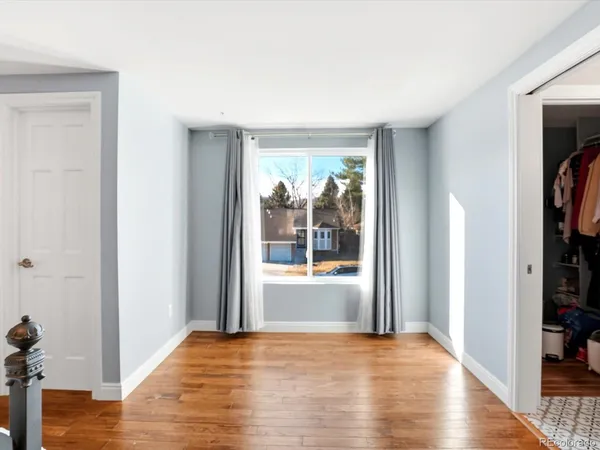 a view of empty room with wooden floor and fan