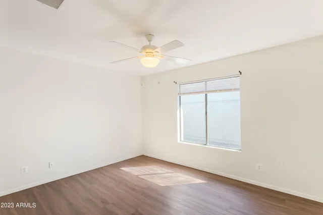 an empty room with a window and a ceiling fan