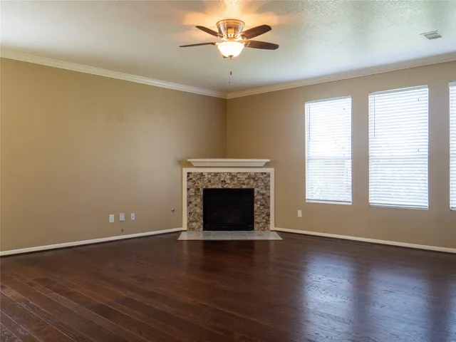 an empty room with windows a fireplace and a ceiling fan