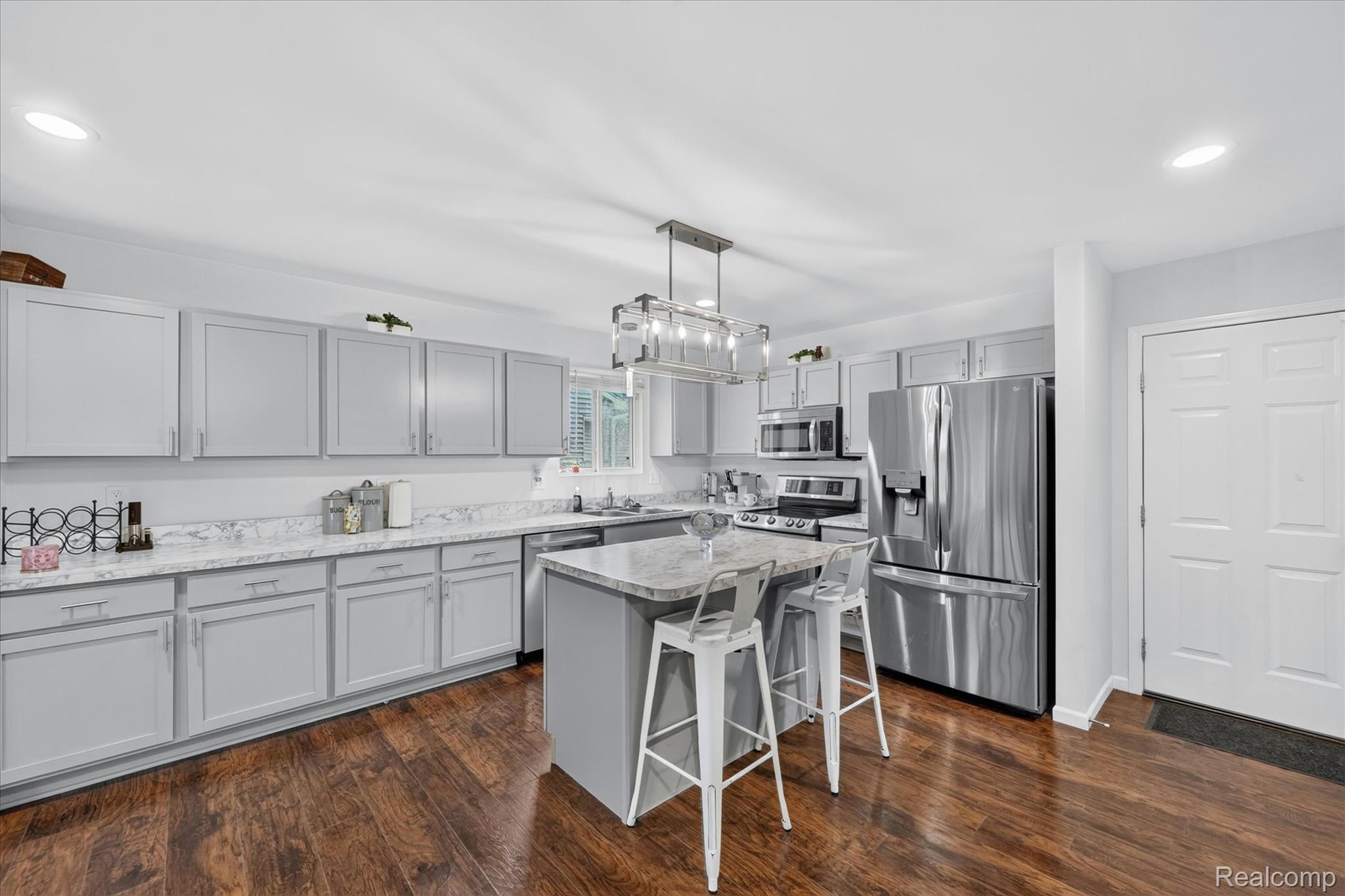 5382 Rural Terrace Waterford, MI 48329 - Photo 13 of 35 Well-appointed kitchen featuring light gray cabinetry, stainless steel appliances, wood-finish flooring, a central island with seating, and recessed lighting