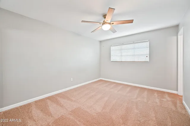 an empty room with a window and a fan